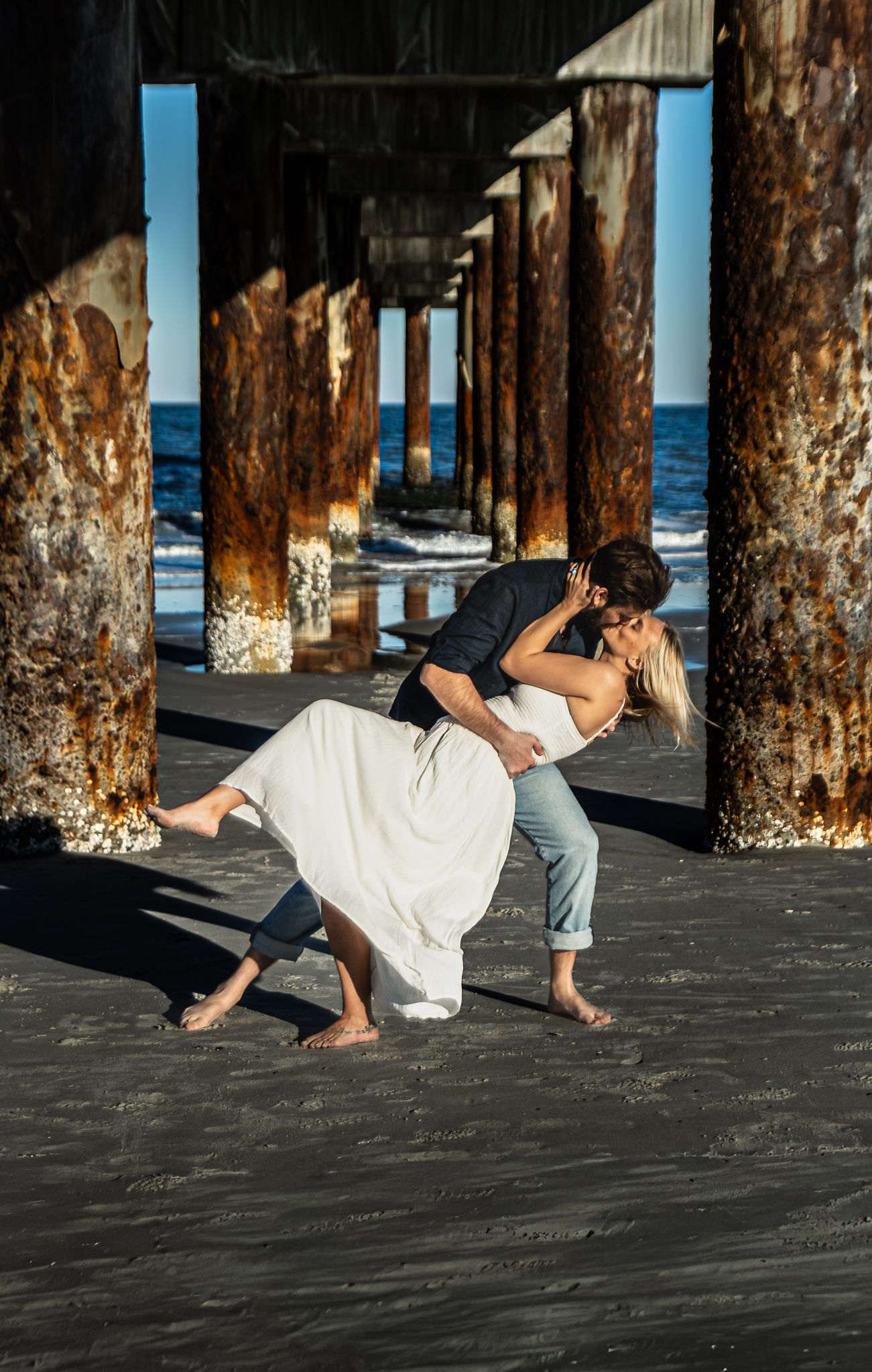 Engagement portraits under the St. Augustine Beach pier, dramatic light by Kaylin Ross Photography