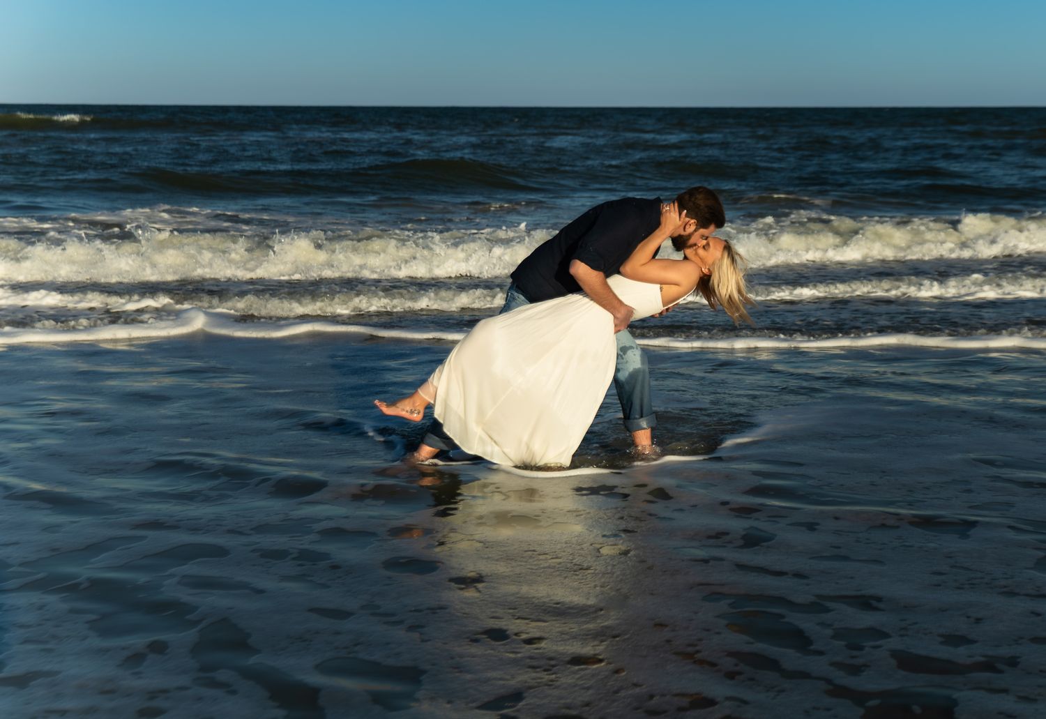 Engagement portraits under the St. Augustine Beach pier, dramatic light by Kaylin Ross Photography