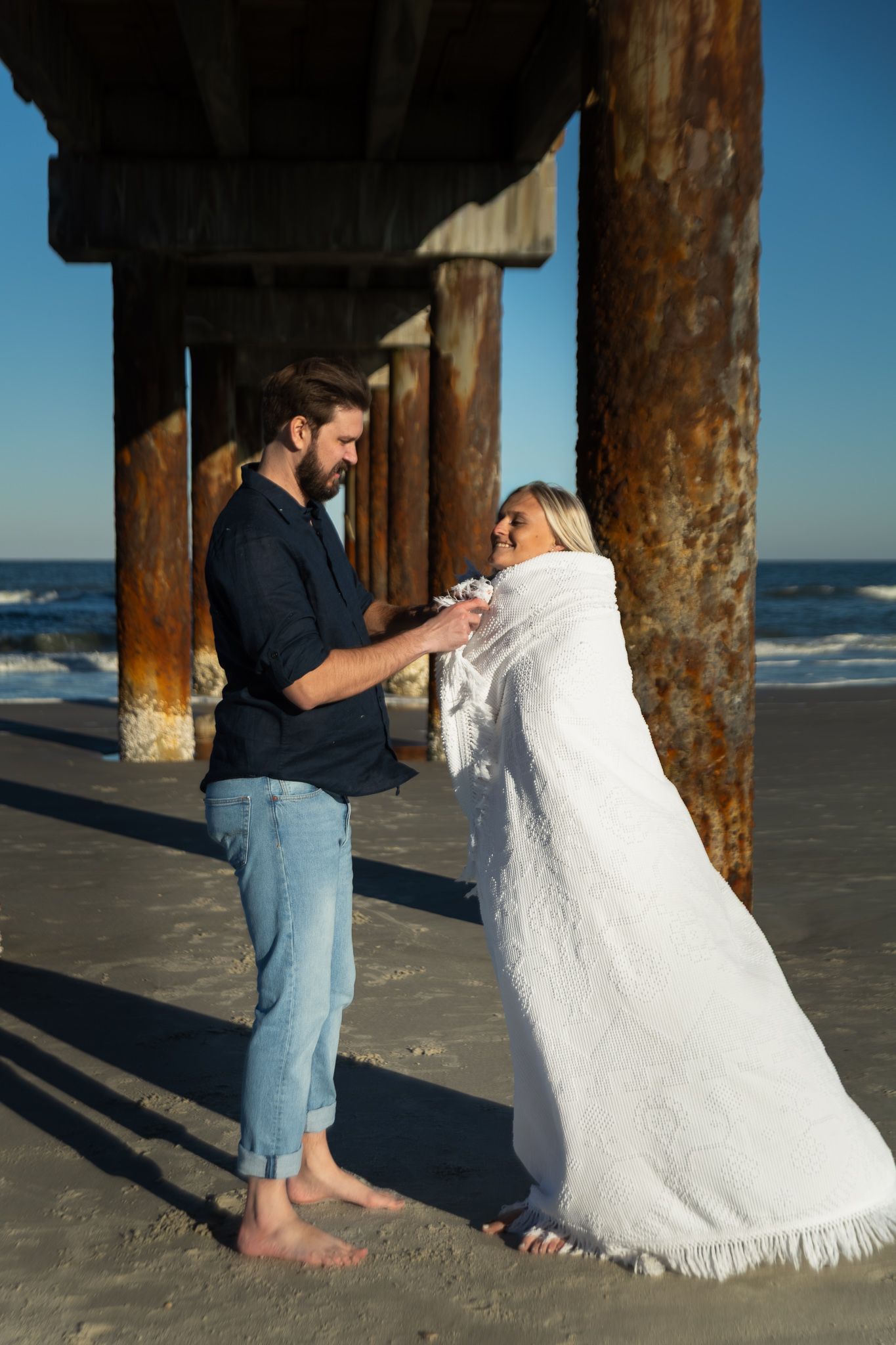 Engagement portraits under the St. Augustine Beach pier, dramatic light by Kaylin Ross Photography