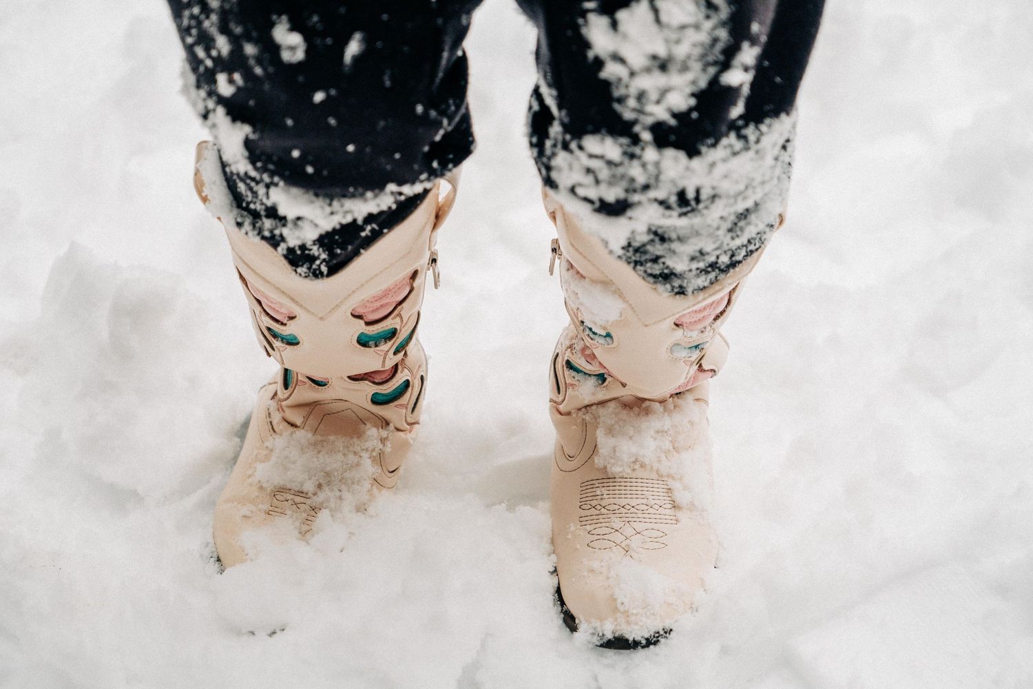 Pink winter boots with black leggings standing in fresh white snow.