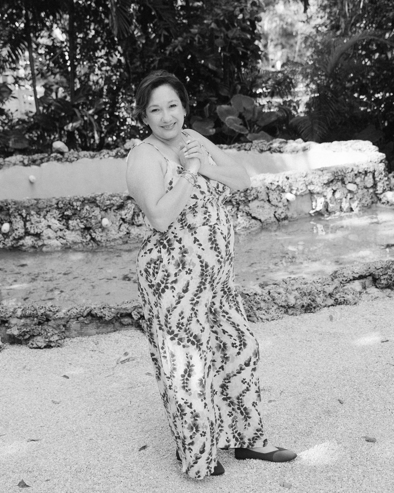 A sequence of black and white photos showing someone in a floral print outfit posing playfully outdoors.
