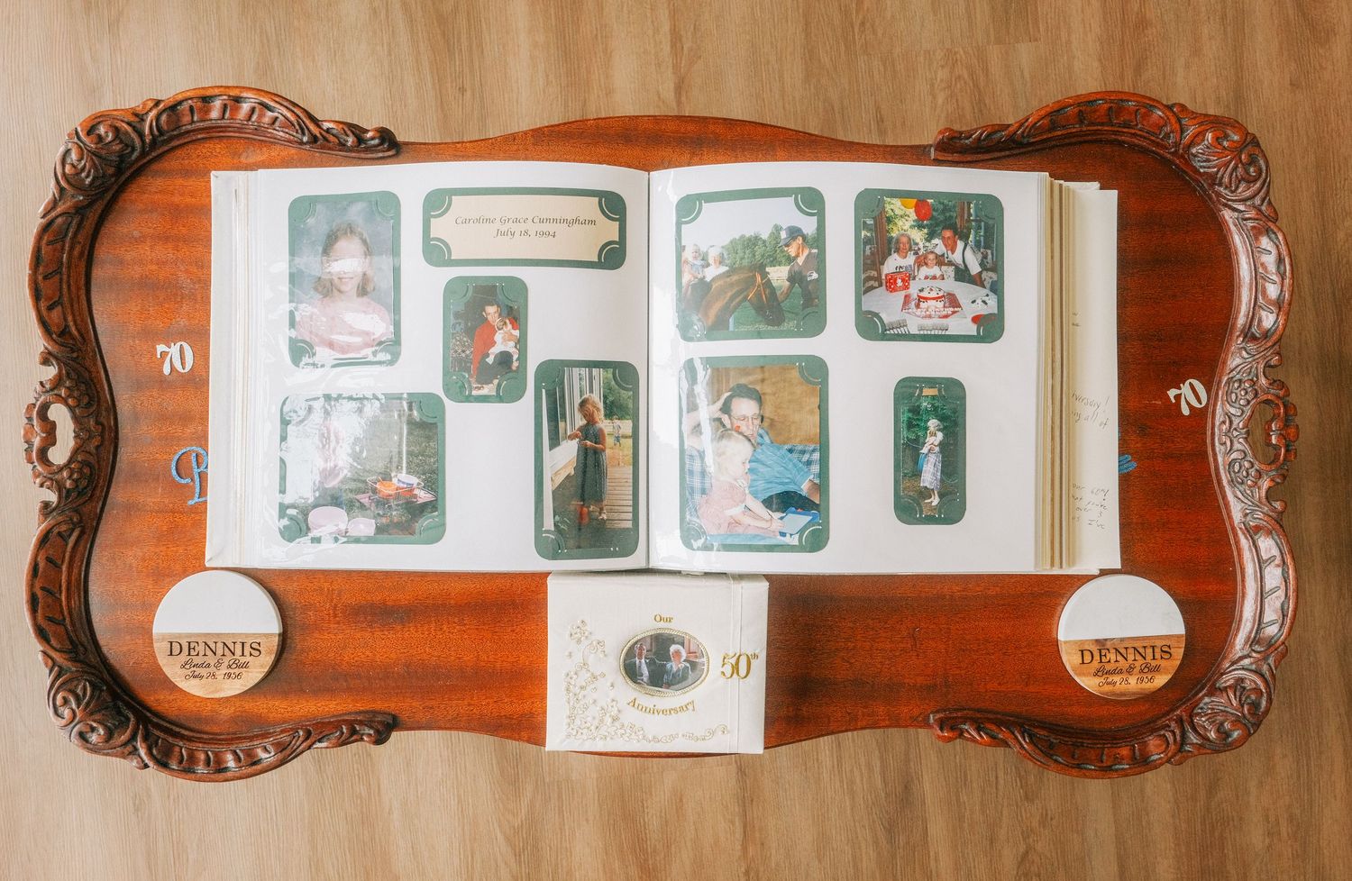 Vintage photo album open on ornate wooden tray displaying antique portrait cards and collectible images.