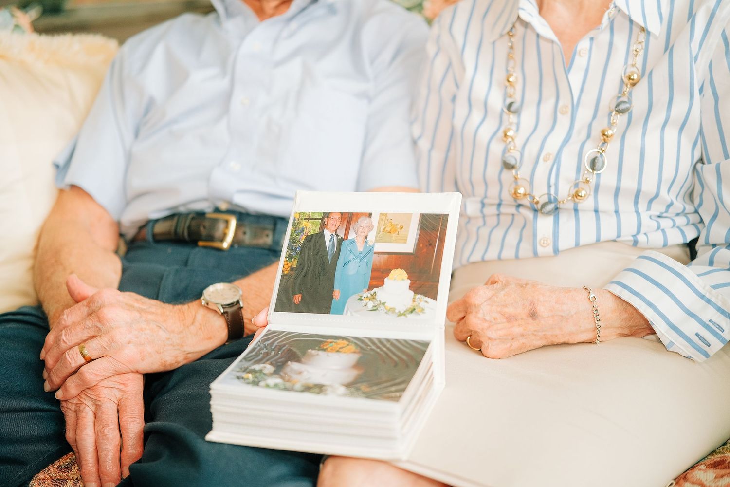 Elderly couple sitting together holding a stack of old wedding photos, reminiscing cherished memories.