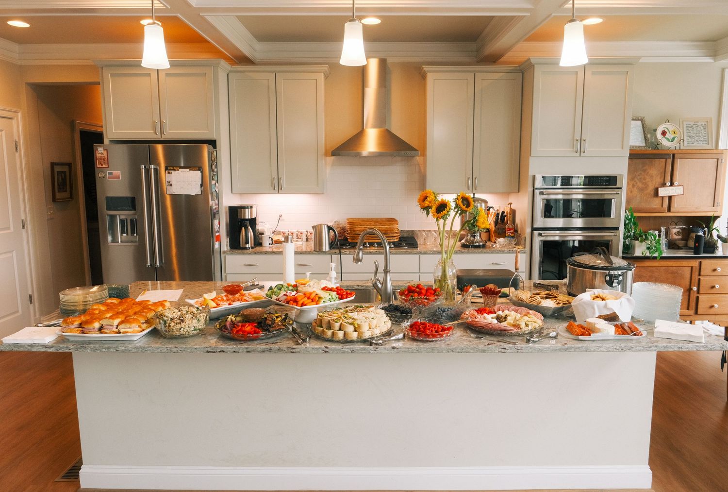 Elegant kitchen island buffet spread with fresh vegetables, fruits, and appetizers for a party.