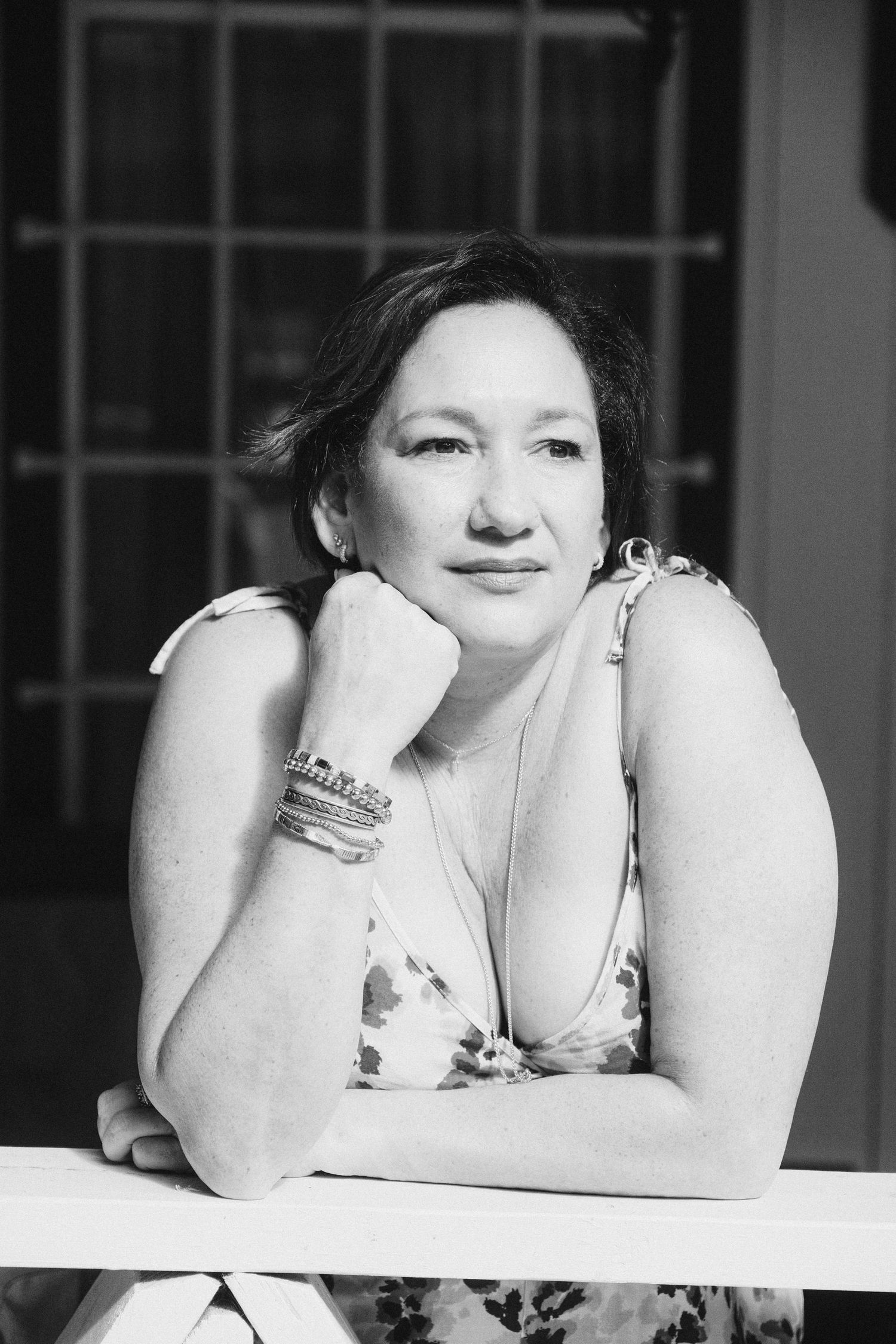 A black and white artistic portrait showing a person lying down and resting their head on their arms in a contemplative pose.