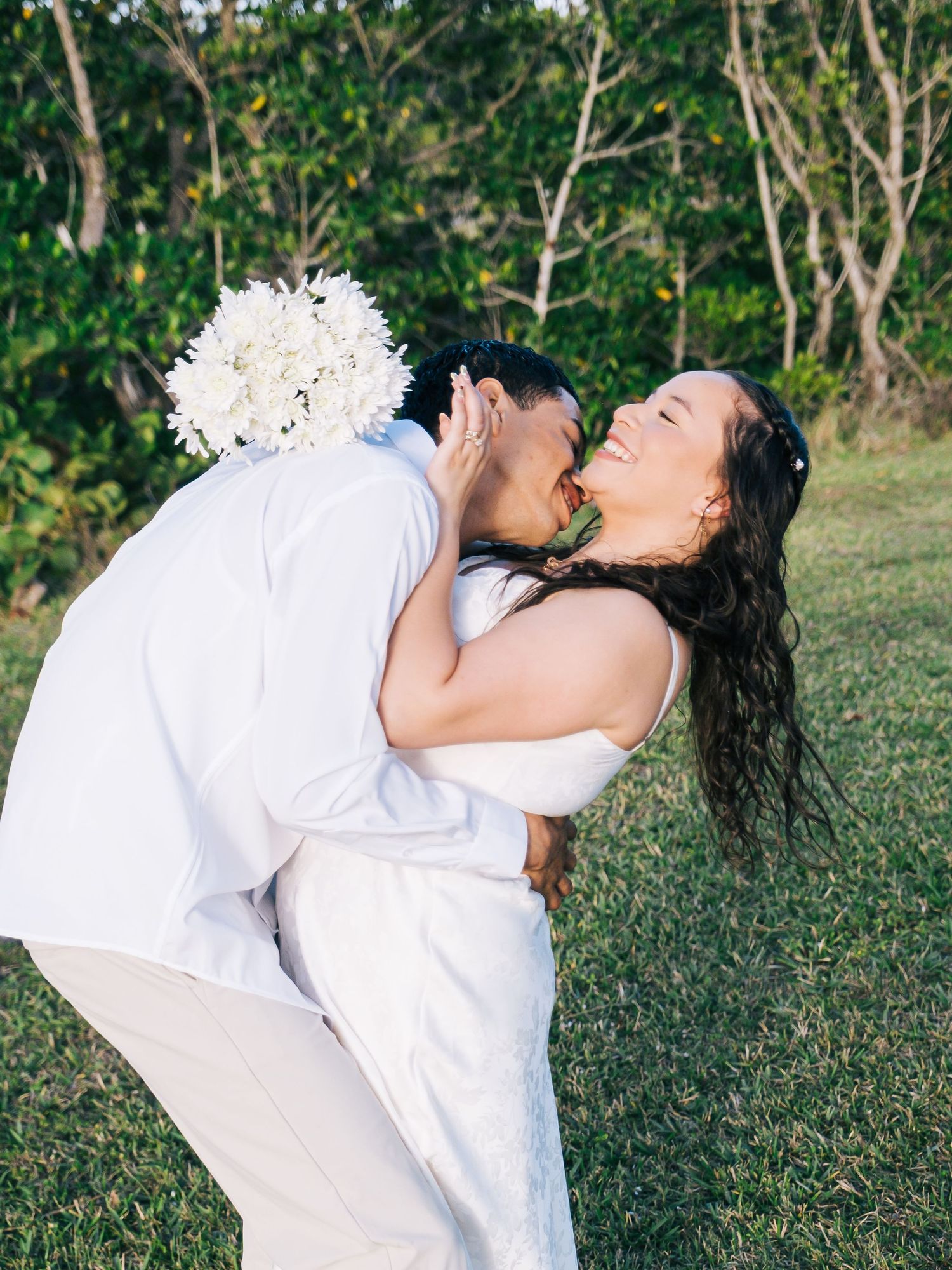 A series of romantic photos showing a couple in white outfits embracing playfully in a lush garden setting.