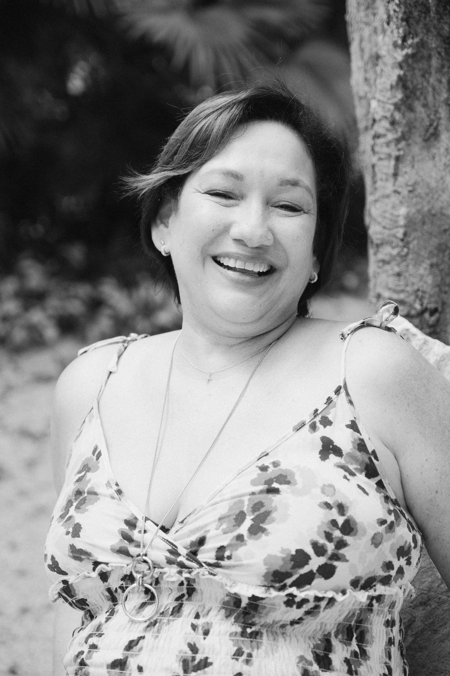 Black and white photo series showing someone in a floral dress leaning against a tree with joyful expressions.