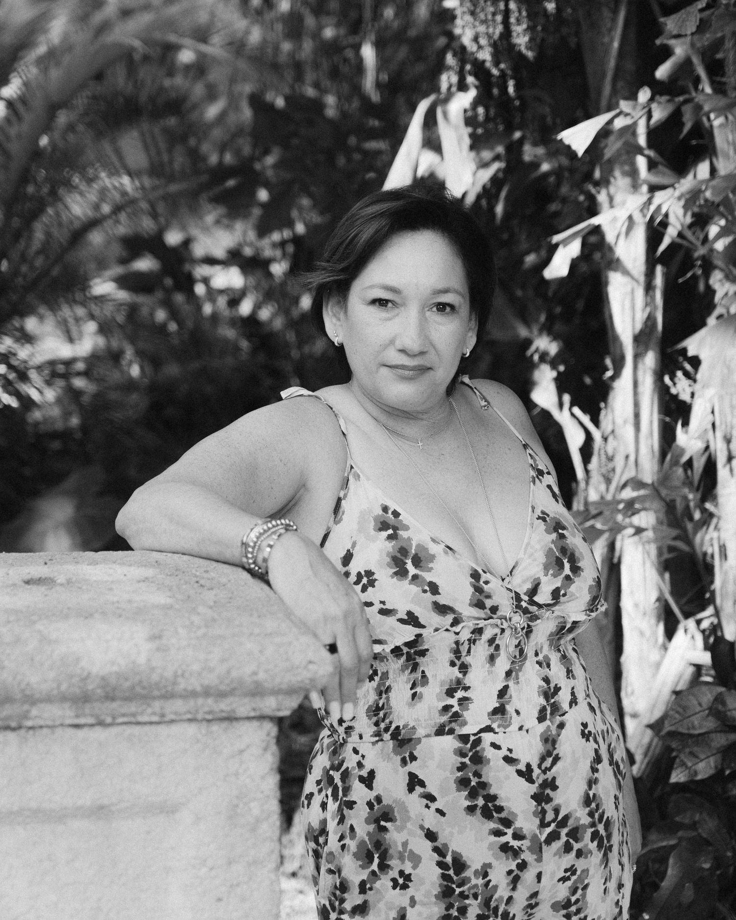A series of black and white portraits showing a woman in a floral dress against a natural outdoor background.
