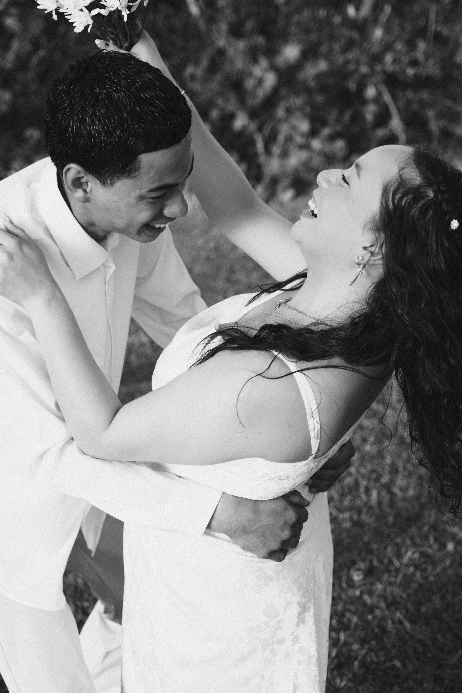 A joyful couple shares a romantic moment outdoors, with the person in white dipping their partner in an elegant dance pose.