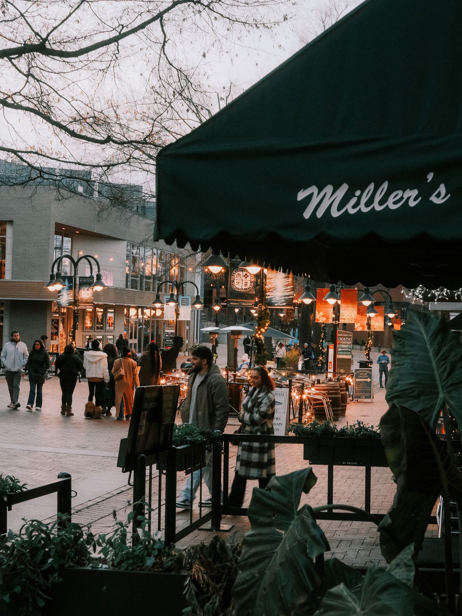 Evening street scene outside Miller's restaurant with outdoor seating and warm lighting.