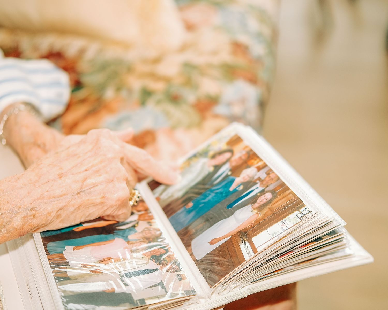 Elderly person's hands holding open a photo album filled with cherished family memories and photographs.