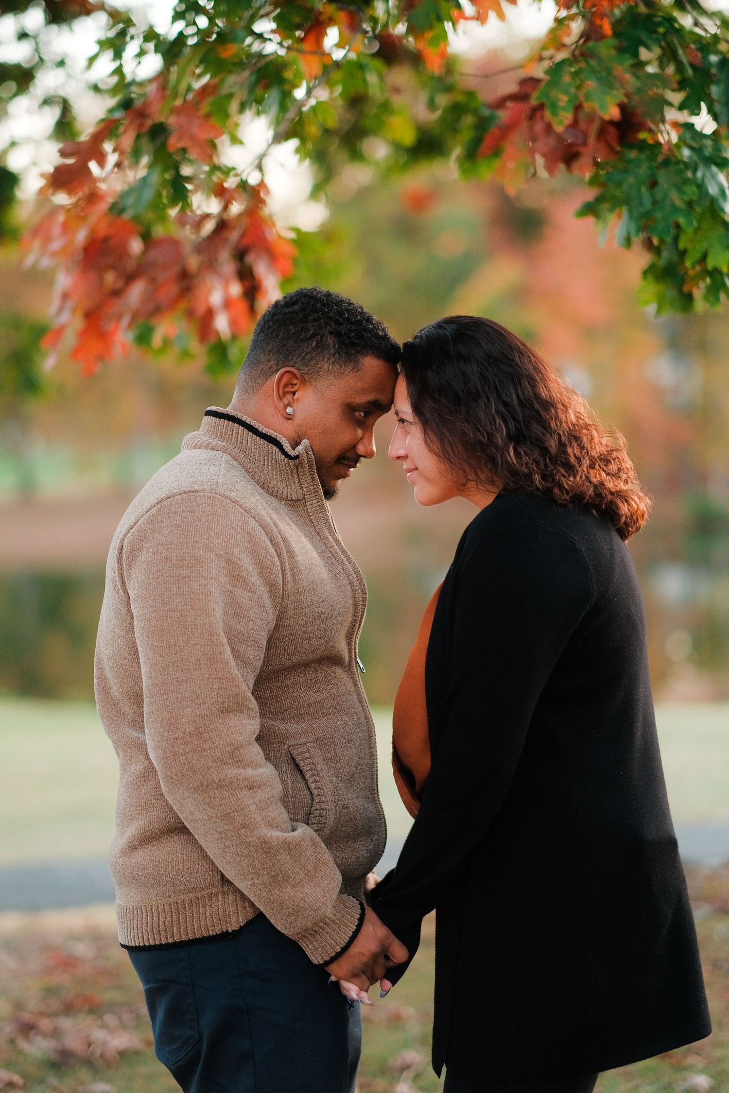 A romantic autumn scene with a couple embracing under colorful fall foliage in a park setting.