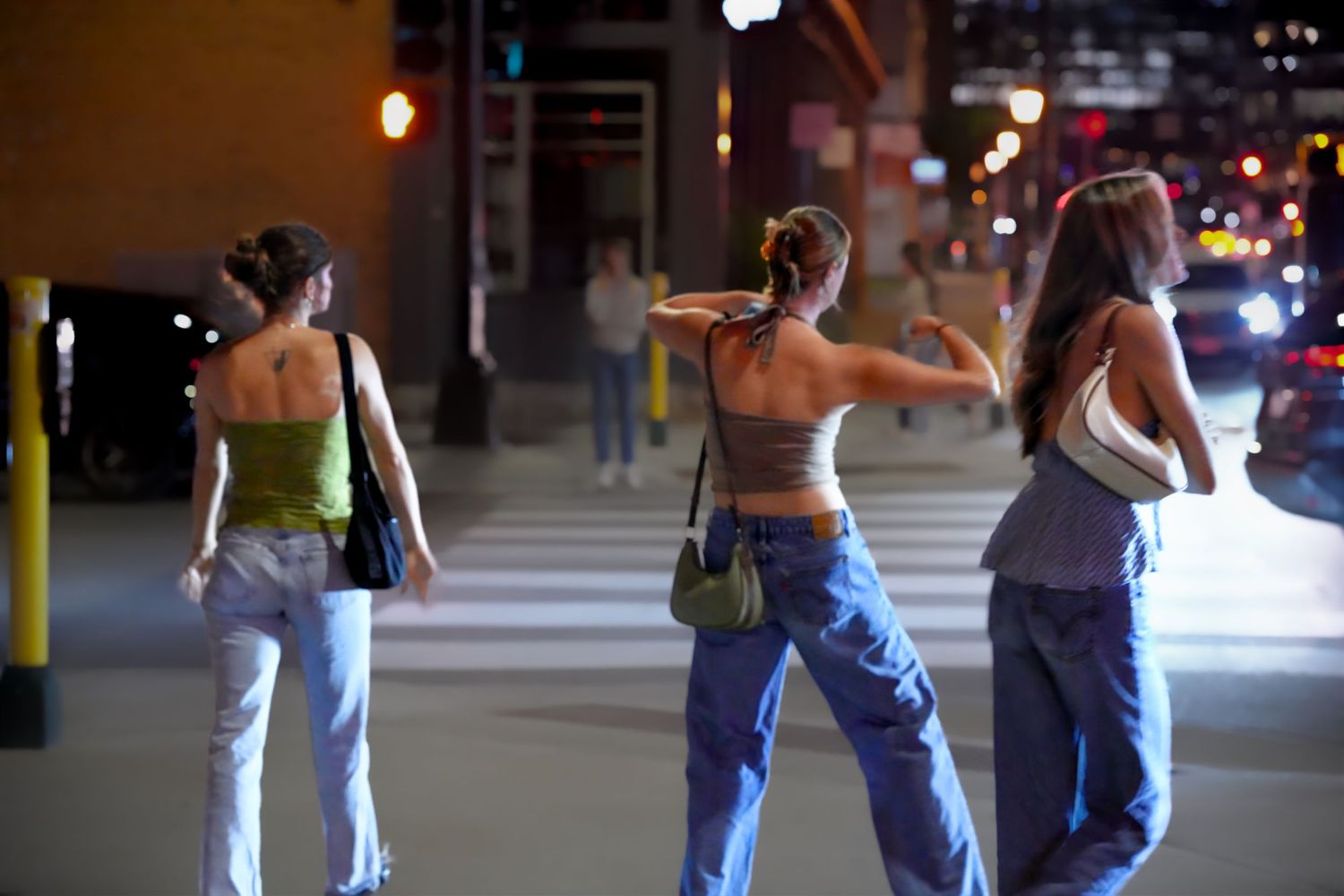 Group of people walking through dimly lit urban street at night.