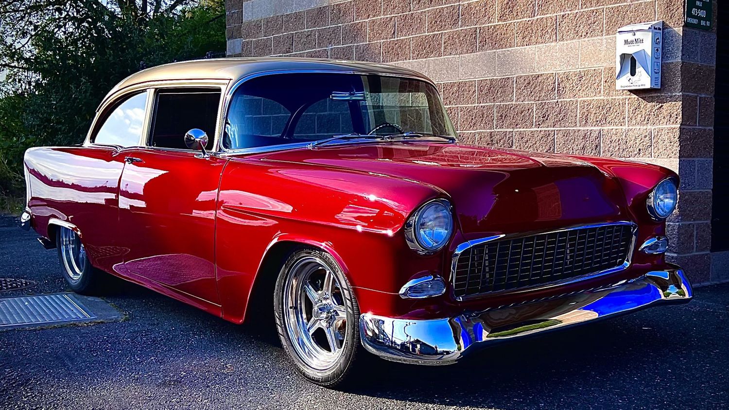Restored 1955 Chevrolet Bel Air custom hot rod in candy red with chrome accents parked outside a building.