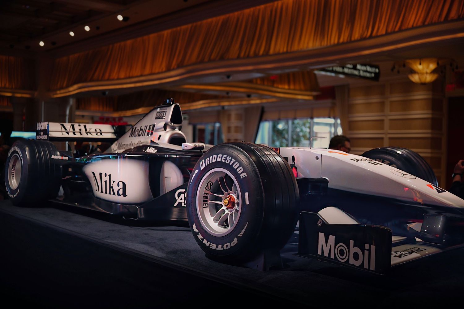 Row of sleek Formula 1 racing cars displayed in dramatic lighting at motorsport exhibition.