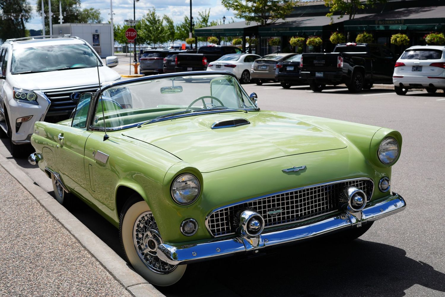 Vintage green Ford Thunderbird convertible parked in a lot, showcasing classic 1950s American automotive design.