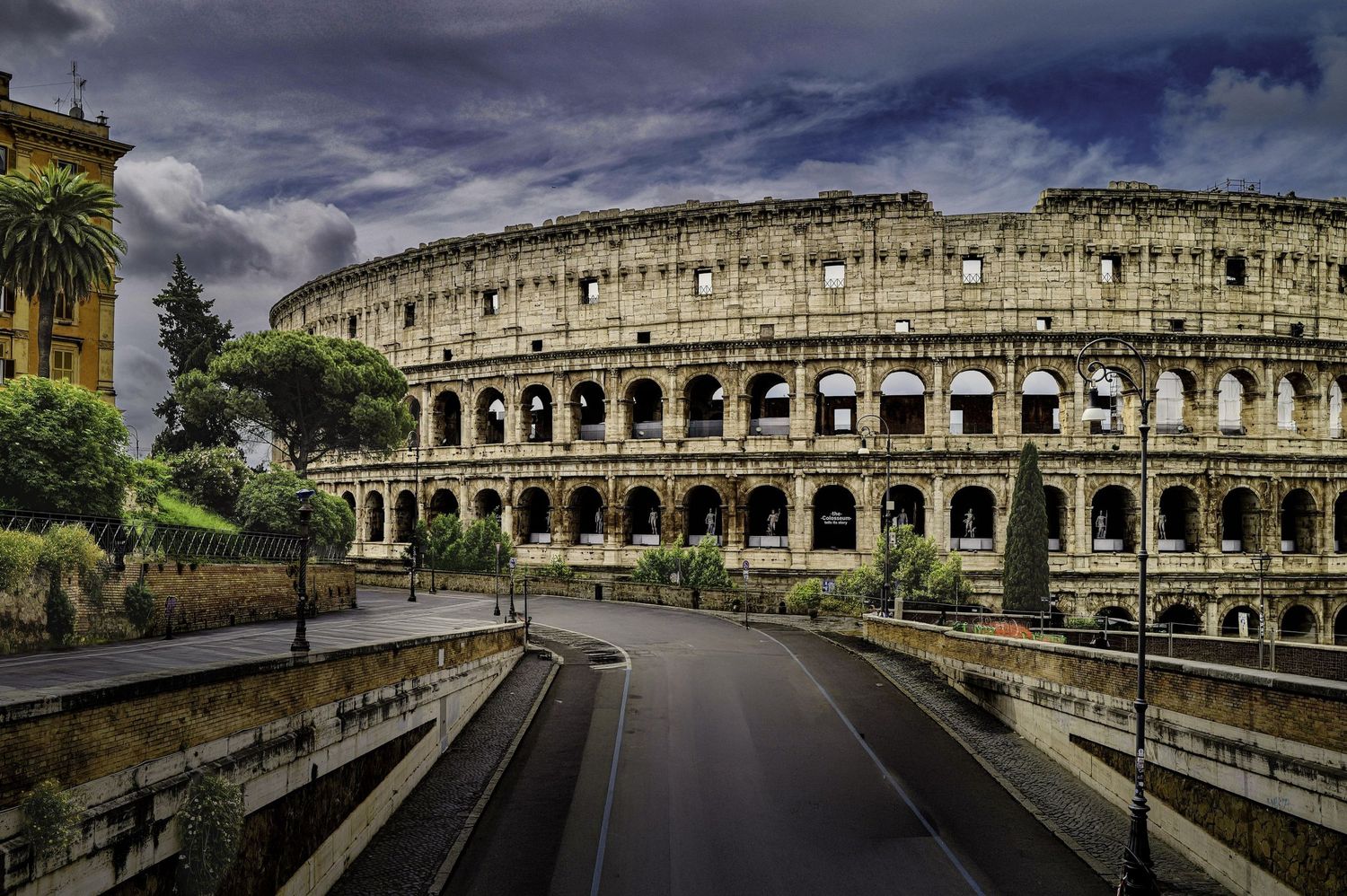 Dramatic view of the ancient Roman Colosseum under stormy skies in Rome, Italy.