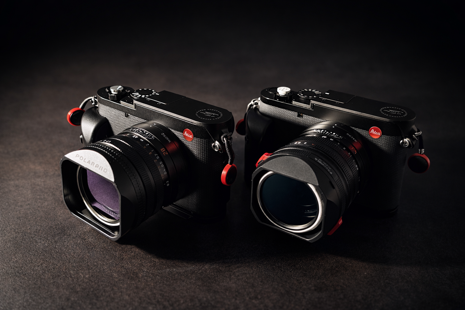 A collection of black camera lenses and equipment arranged in a dramatic dark lighting setup against a black background.