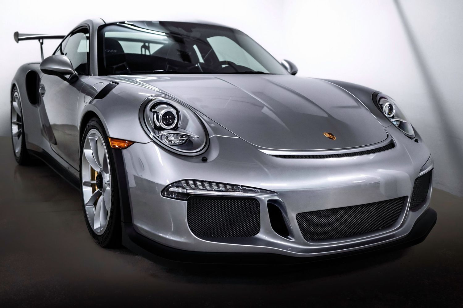Silver Porsche sports car showcased in dramatic studio lighting.