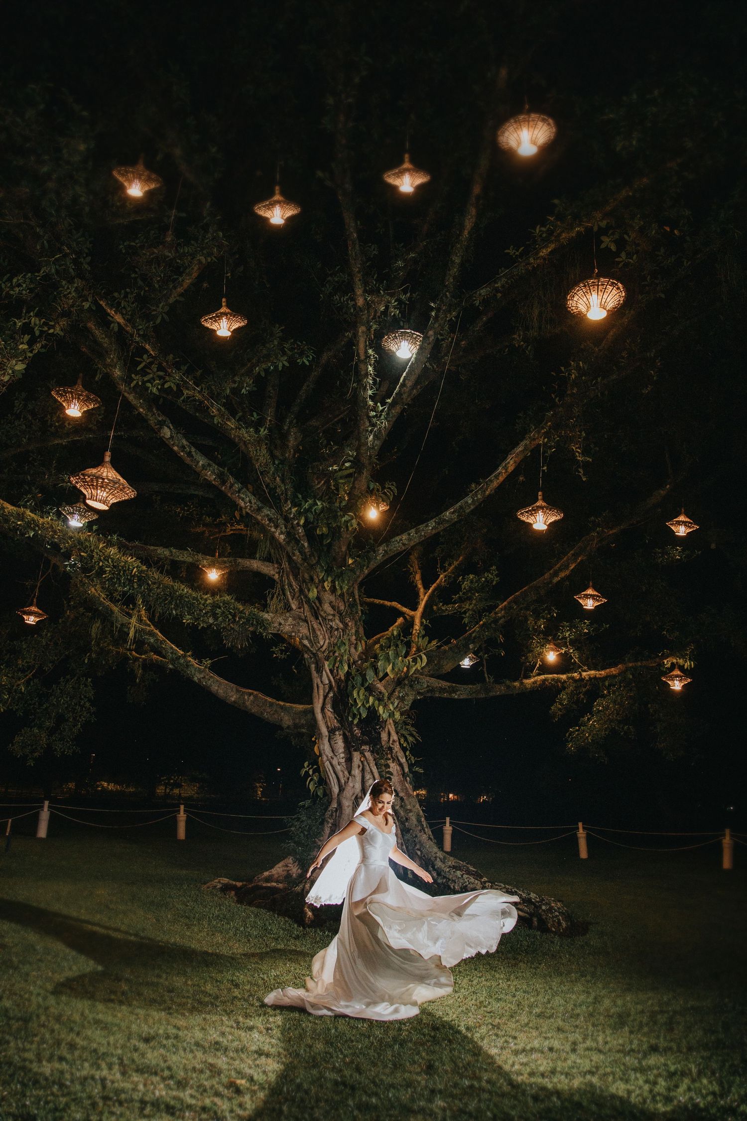Novia con vestido amplio bajo árbol iluminado de noche, estilo editorial en Guatemala / Bride under night tree, editorial wedding photo.