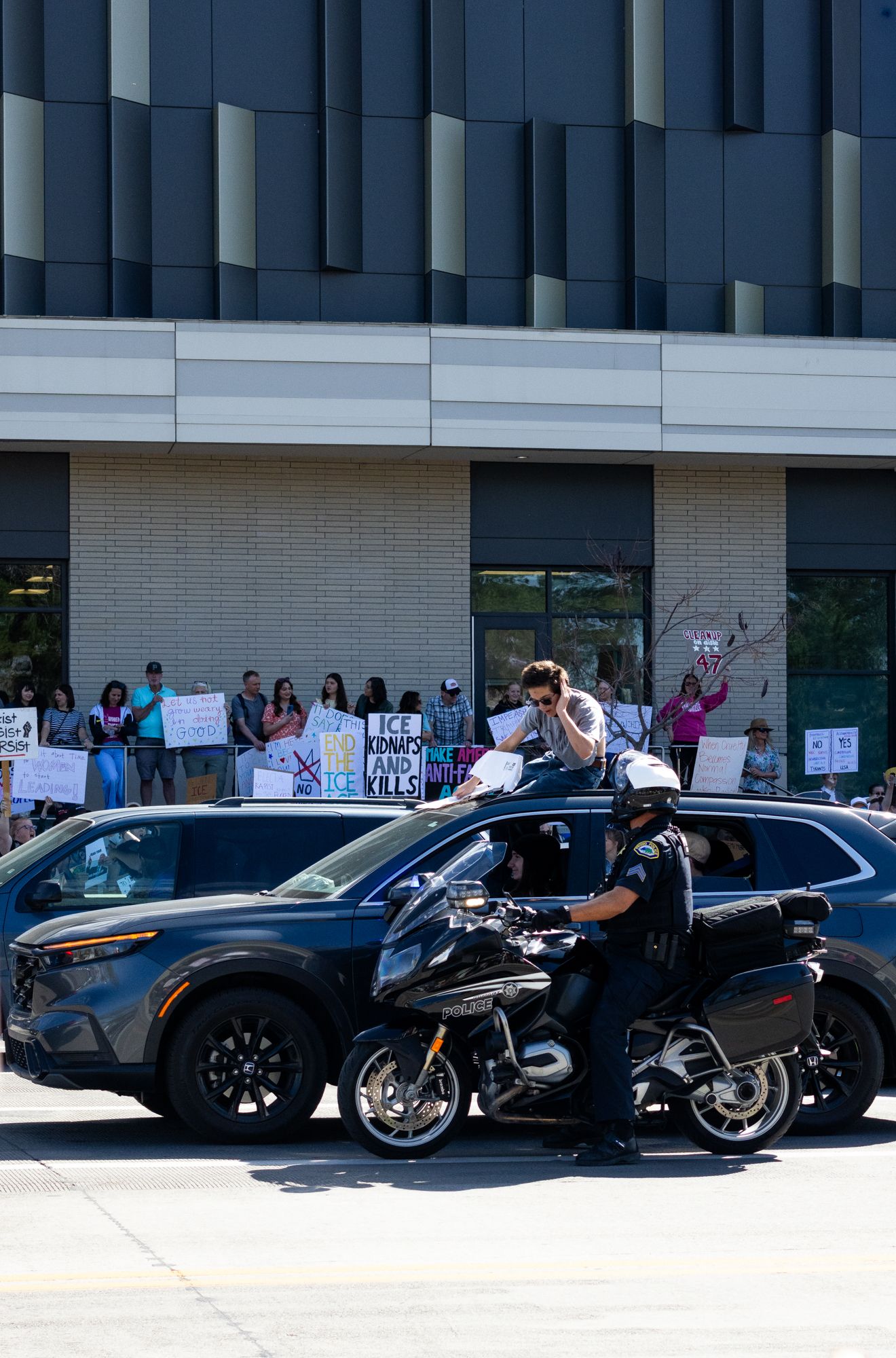 Urban protest scene with raised sign and passing traffic. Dynamic street moment capturing movement, tension, and civic engagement.