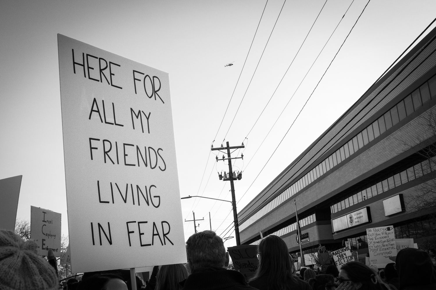 Powerful B&W documentary photography of a public protest. Hand-drawn sign in an urban setting. Authentic imagery for news and editorial use.