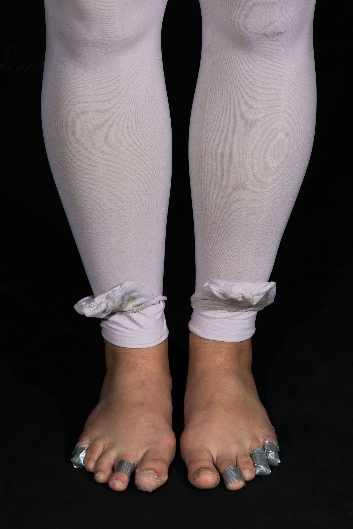 Technical footwear detail. Capturing the utilitarian reality of athletic preparation with duct-taped toes and white tights. Premium dance an