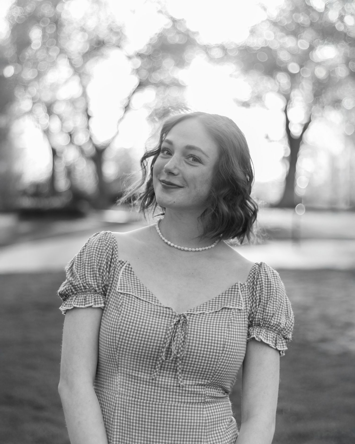 Timeless elegance in monochrome. A soft, black-and-white portrait of a woman in a gingham dress, radiating a classic and soulful charm.