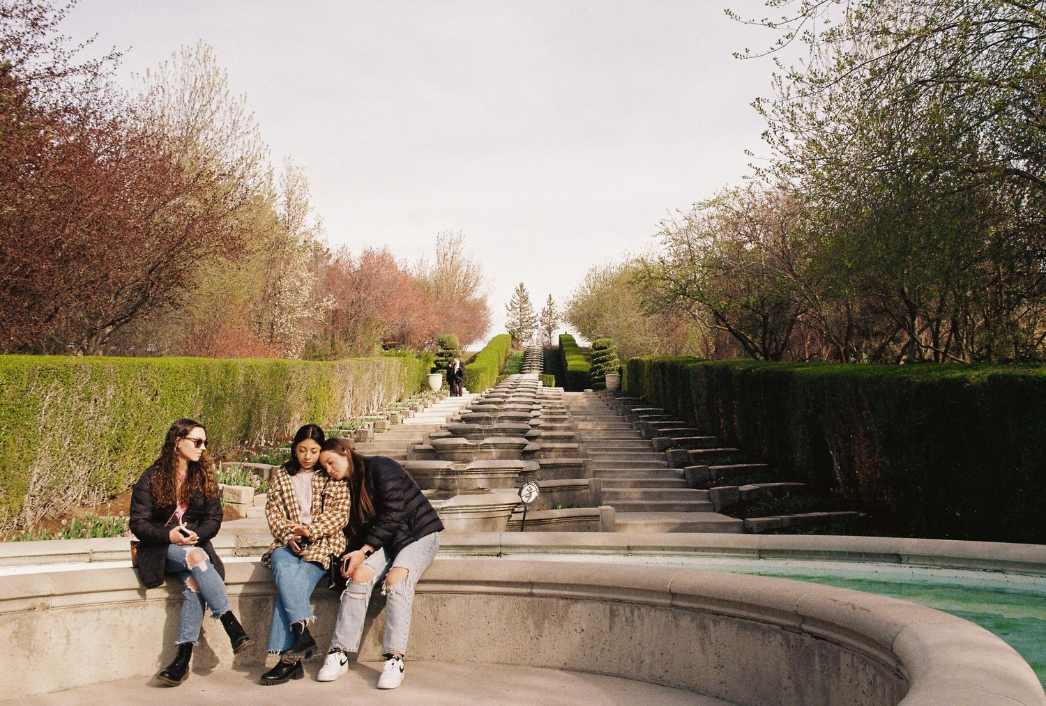 Candid lifestyle photography featuring a shared moment by a tiered garden fountain, ideal for travel branding and editorial storytelling.