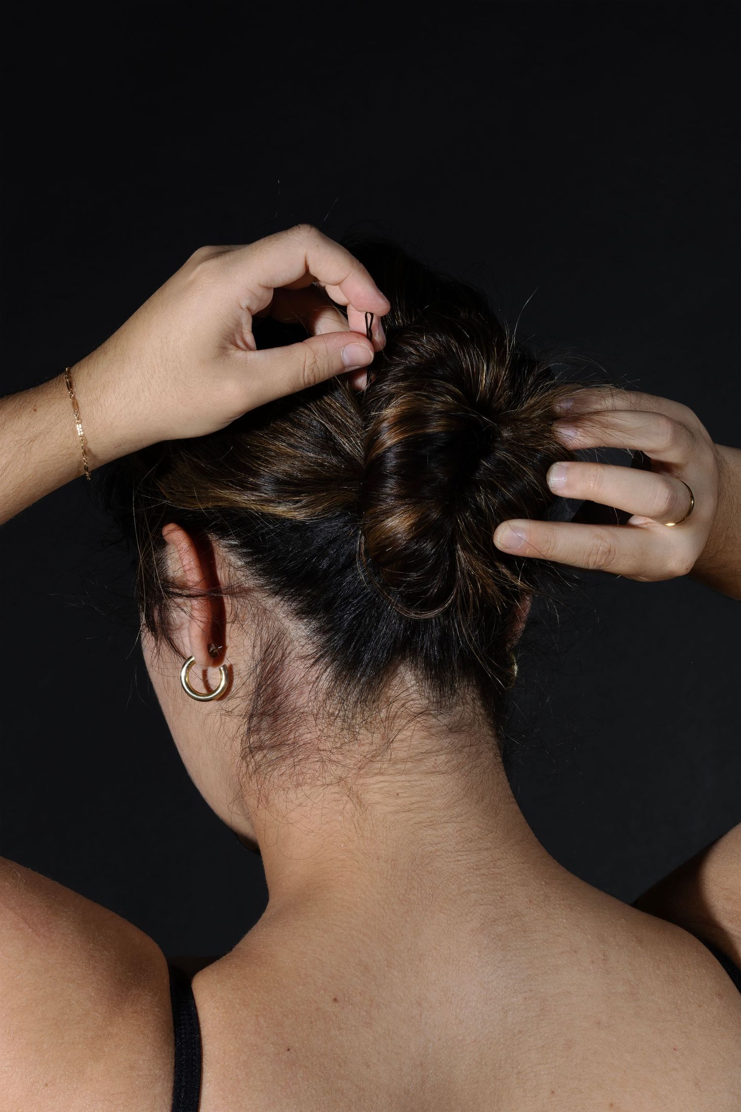 Atmospheric studio portrait of hair being styled. Intimate, high-contrast study of form and accessories. Professional beauty photography.