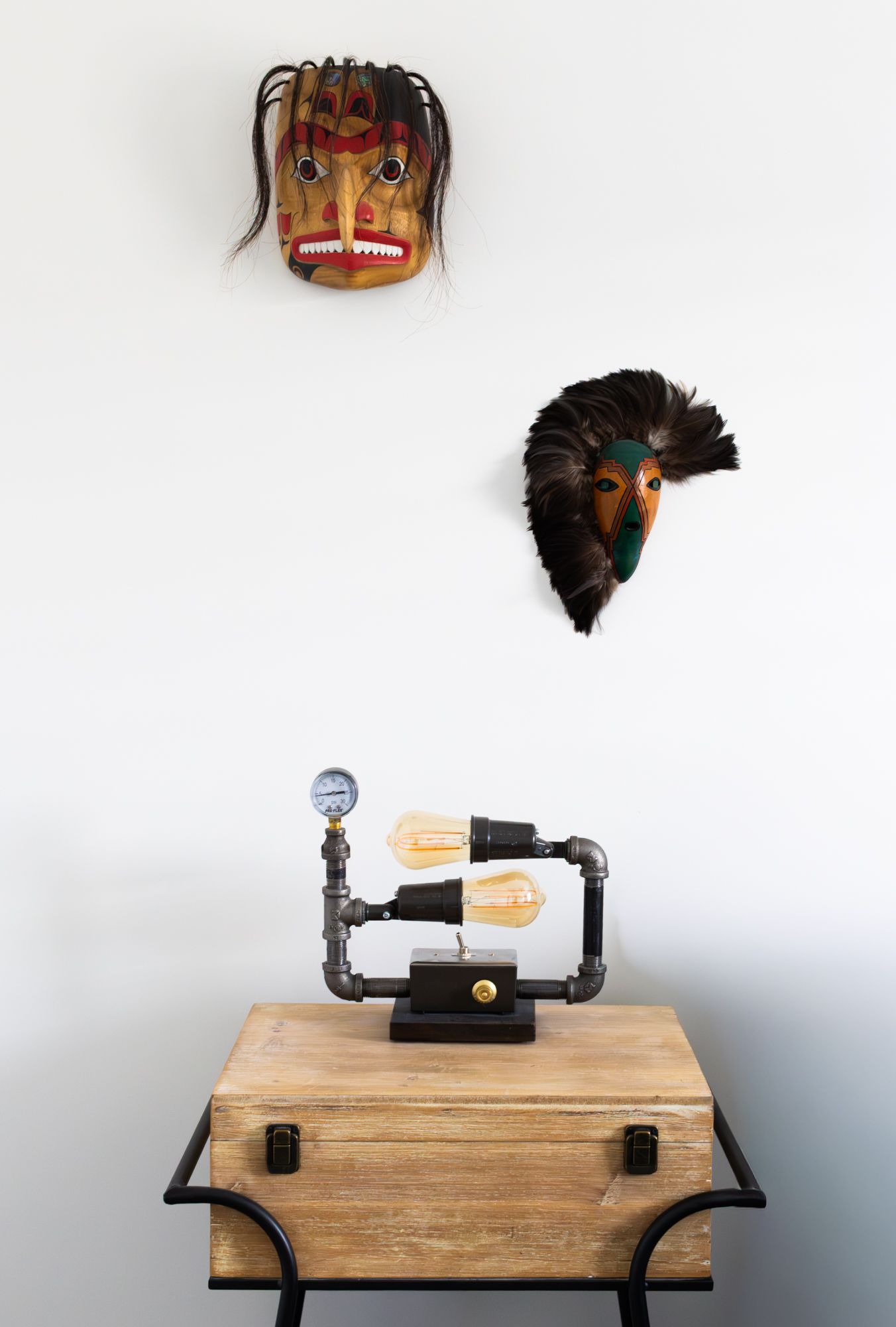 Clean interior photography featuring a custom industrial pipe lamp and tribal wall art, highlighting unique textures and curated home decor.