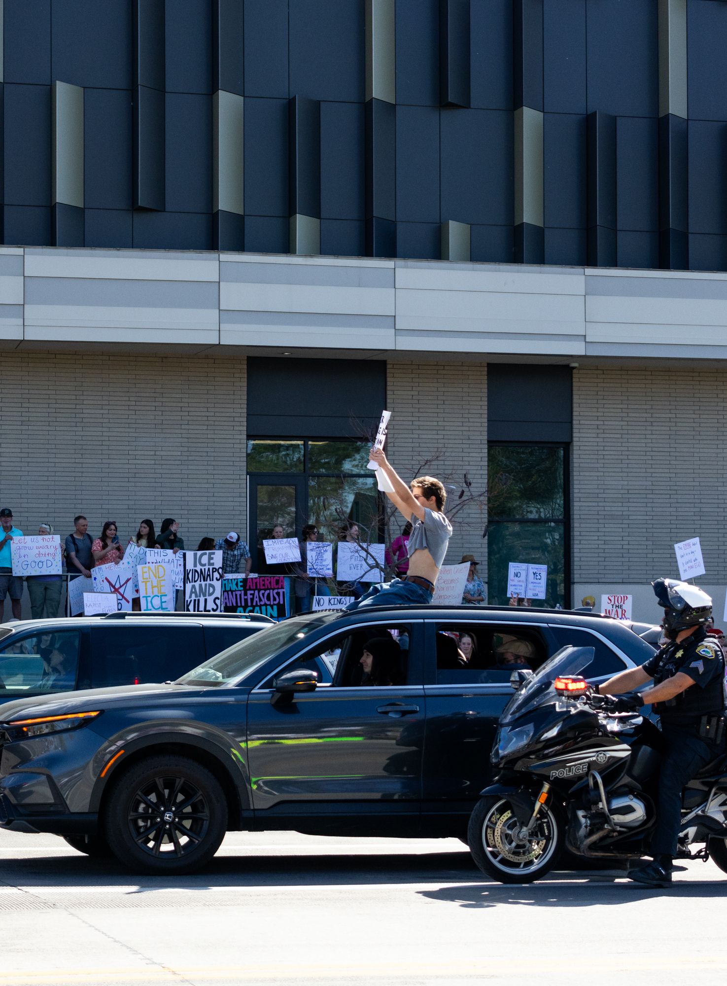 Urban protest scene with raised sign and passing traffic. Dynamic street moment capturing movement, tension, and civic engagement.