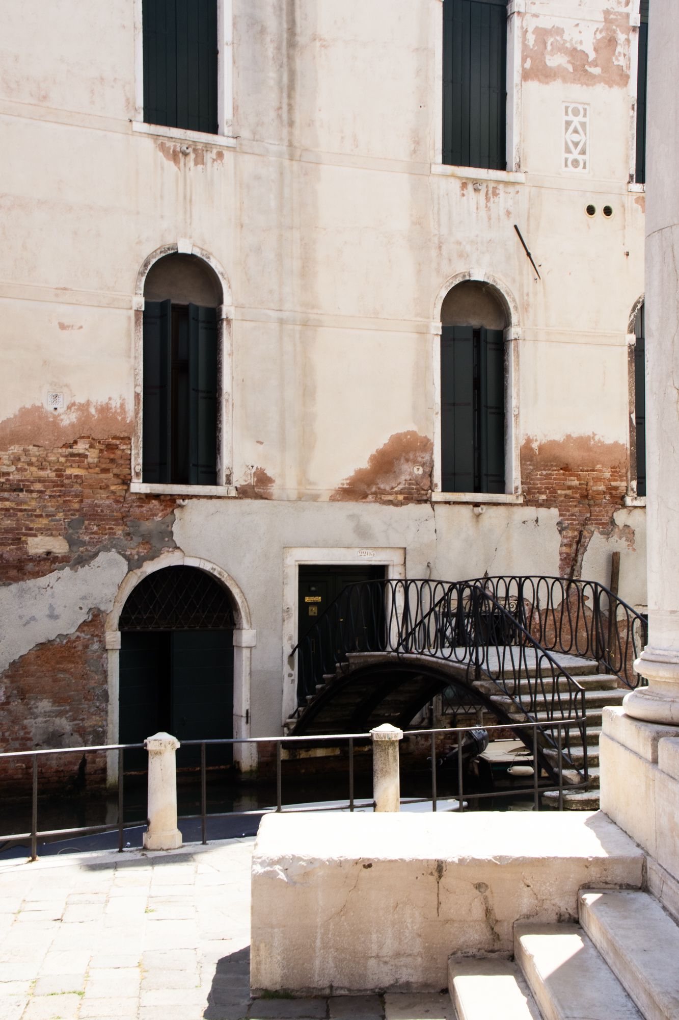 Admire the weathered textures of historic Venetian architecture, featuring arched windows and a private stone bridge over a quiet canal.