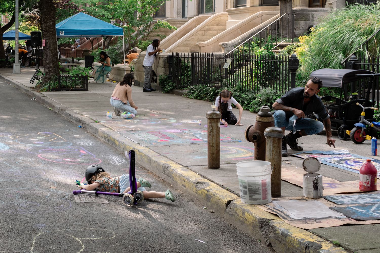 Children create colorful chalk art on a sunlit Brooklyn sidewalk, capturing a heartwarming moment of community and play in New York City.