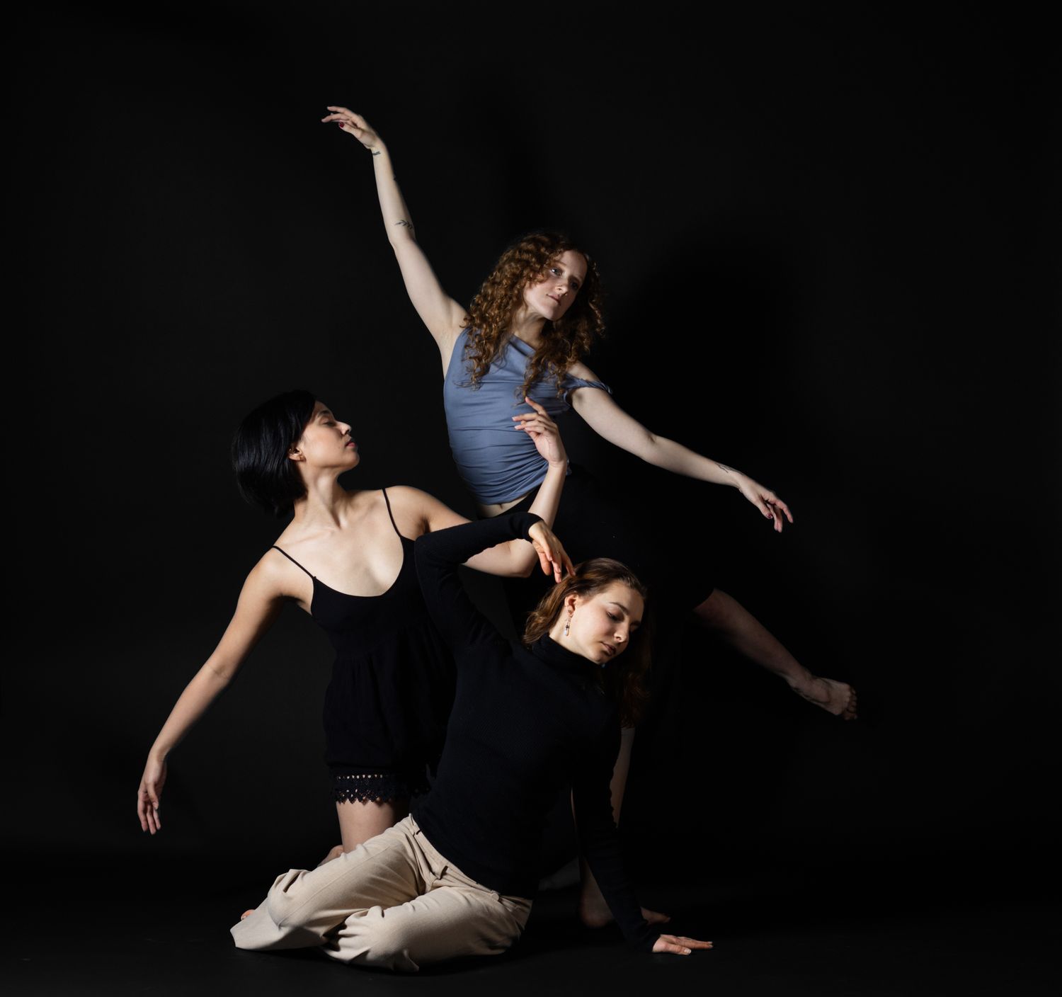 Professional contemporary dance photography. Dynamic trio composition with dramatic studio lighting. Premium imagery for dance companies.