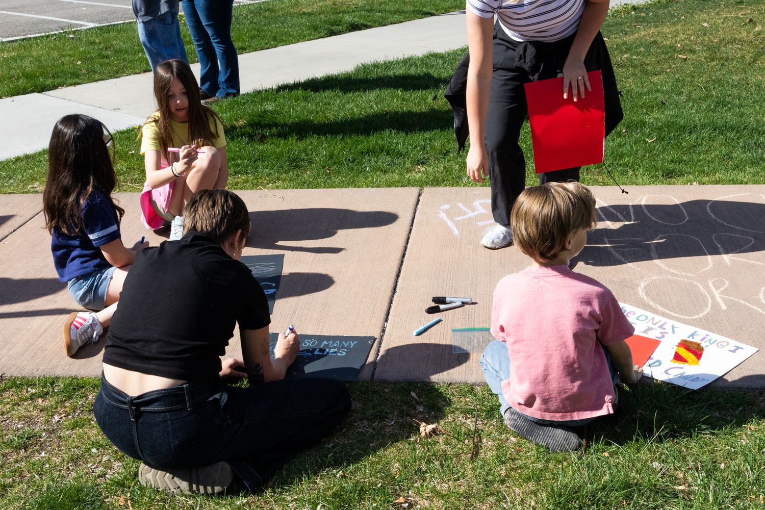 Community protest scene with children drawing chalk messages. Sunlit moment capturing creativity, connection, and civic engagement.
