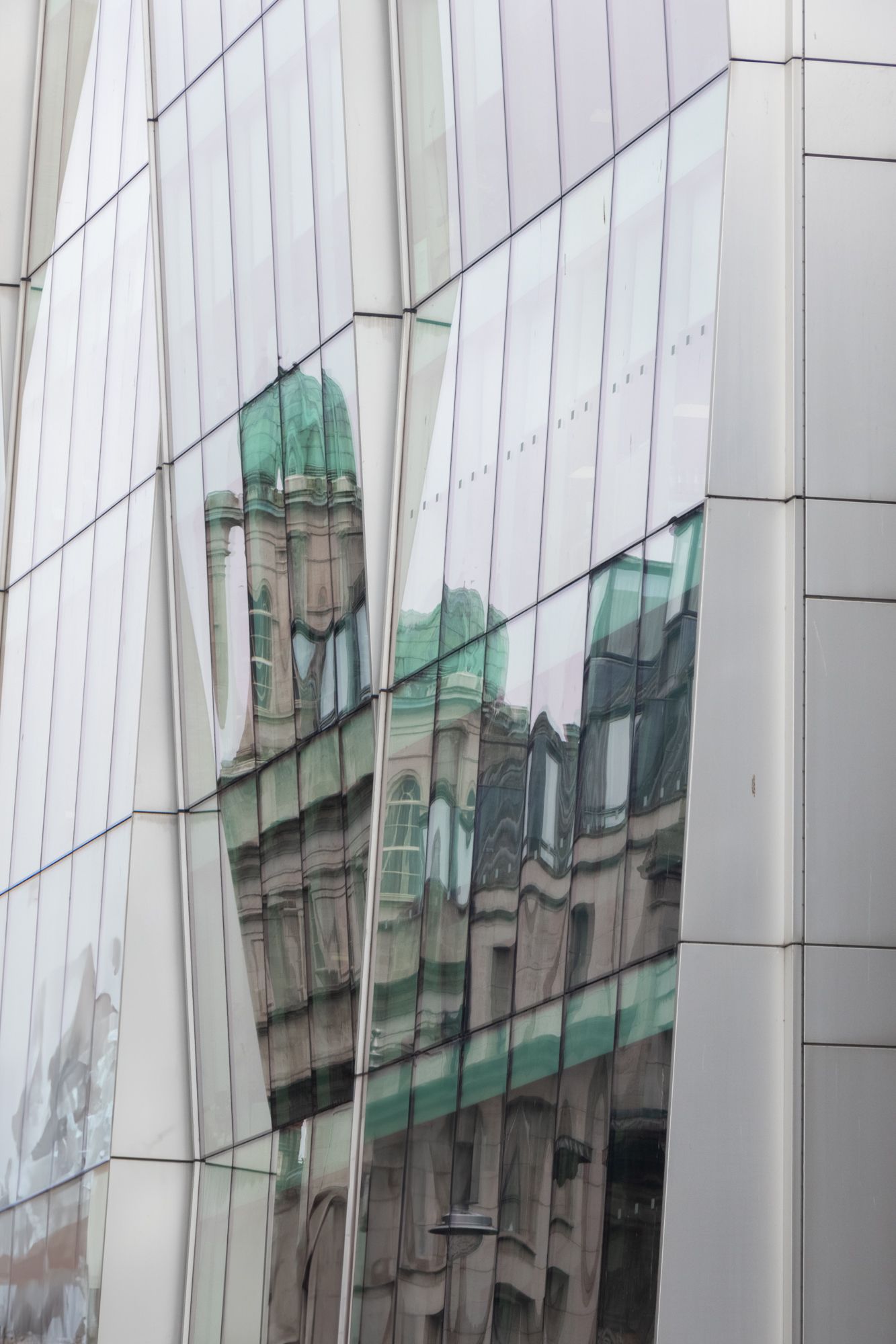 Architectural study of glass reflections. Focus on the fractured, geometric distortion of a traditional building in a modern facade. Rhythm