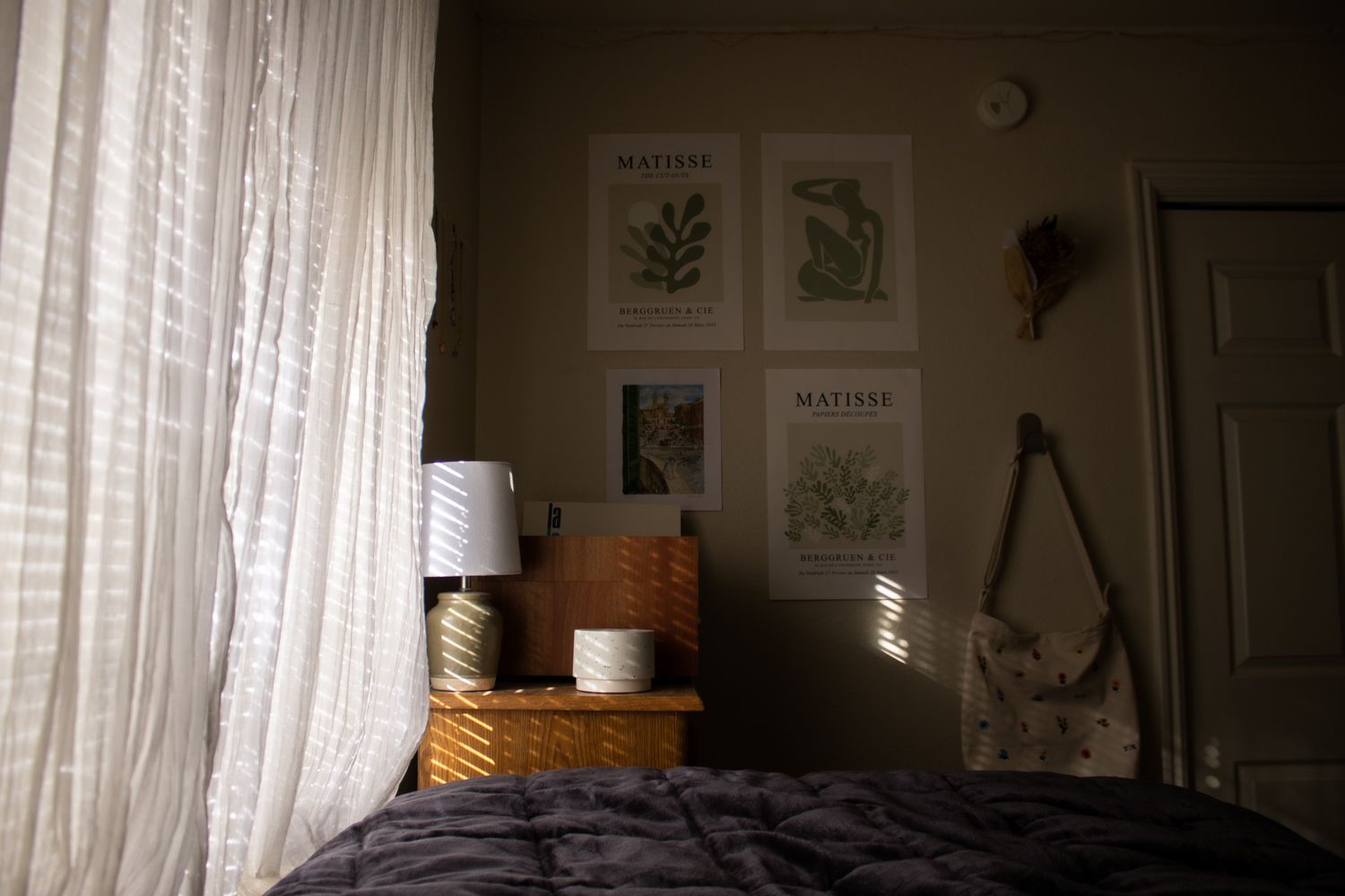 Atmospheric indoor study featuring morning light through sheer curtains. Elegant wall art and bedside details. Premium for design blogs.