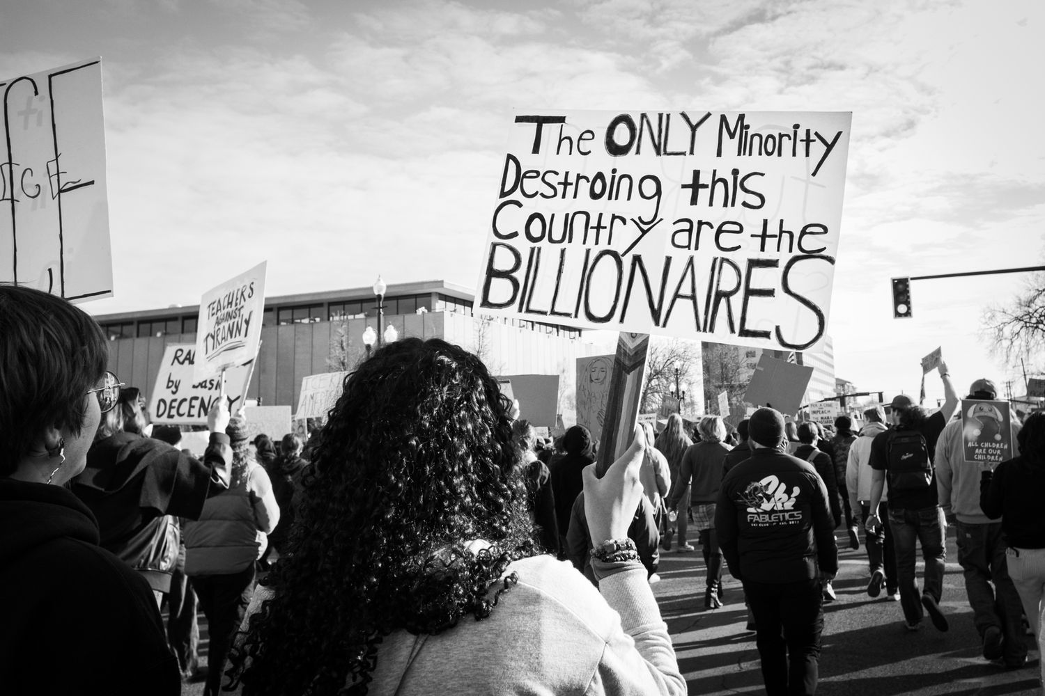 Powerful B&W documentary photography. A woman holds a handwritten sign in a city protest crowd. Authentic imagery for news and editorial.