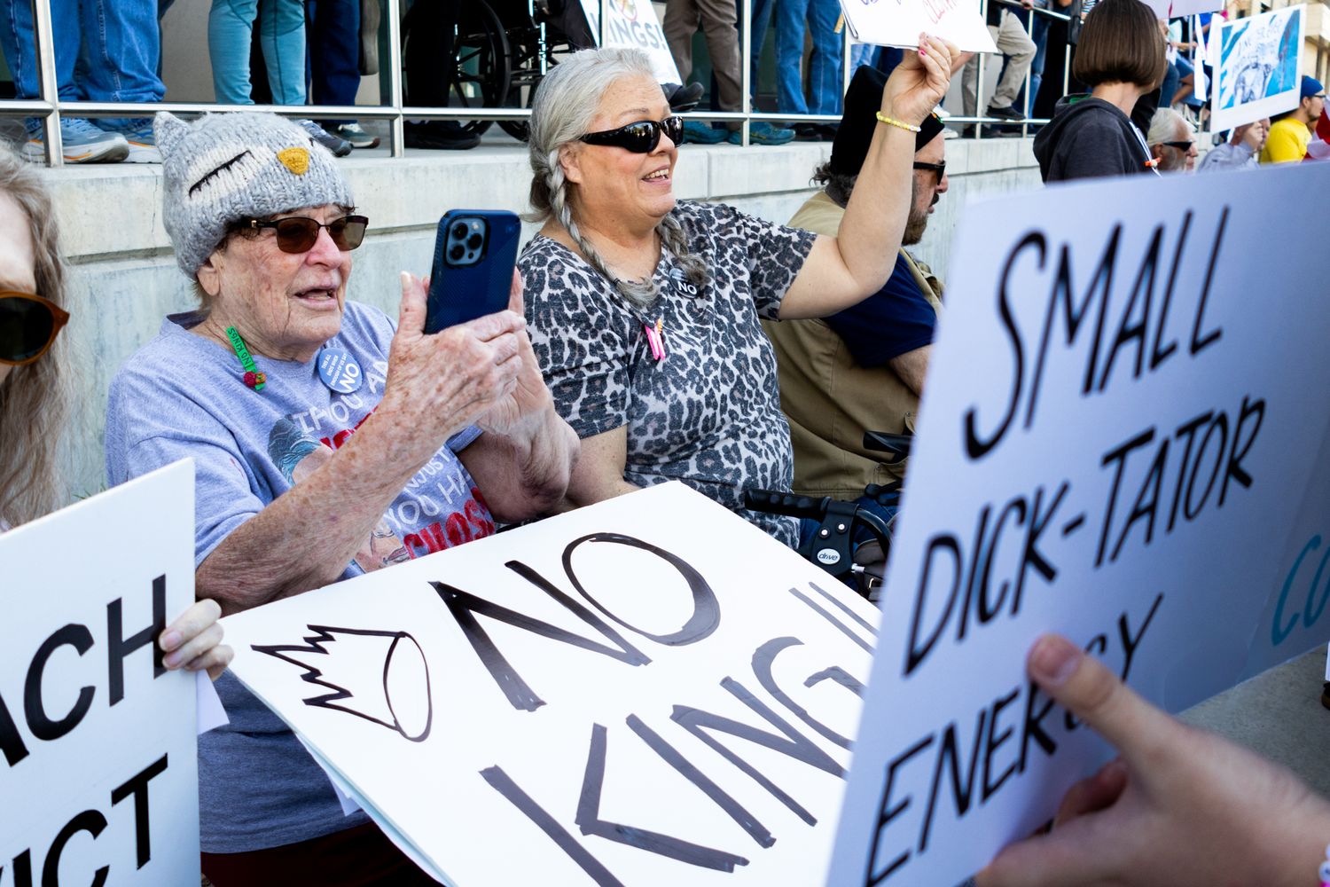 A candid documentary photo of demonstrators holding hand-painted signs during a spirited public protest, capturing the community's energy.