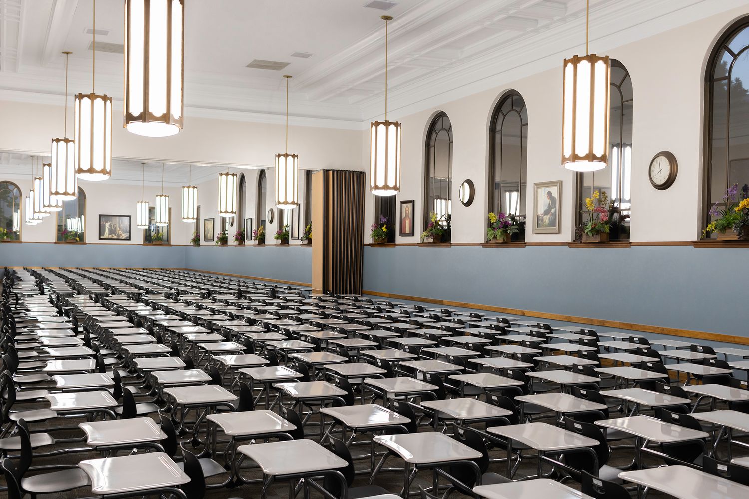 Expansive interior photography of a large study hall featuring rhythmic rows of desks and modern pendant lighting, ideal for institutional