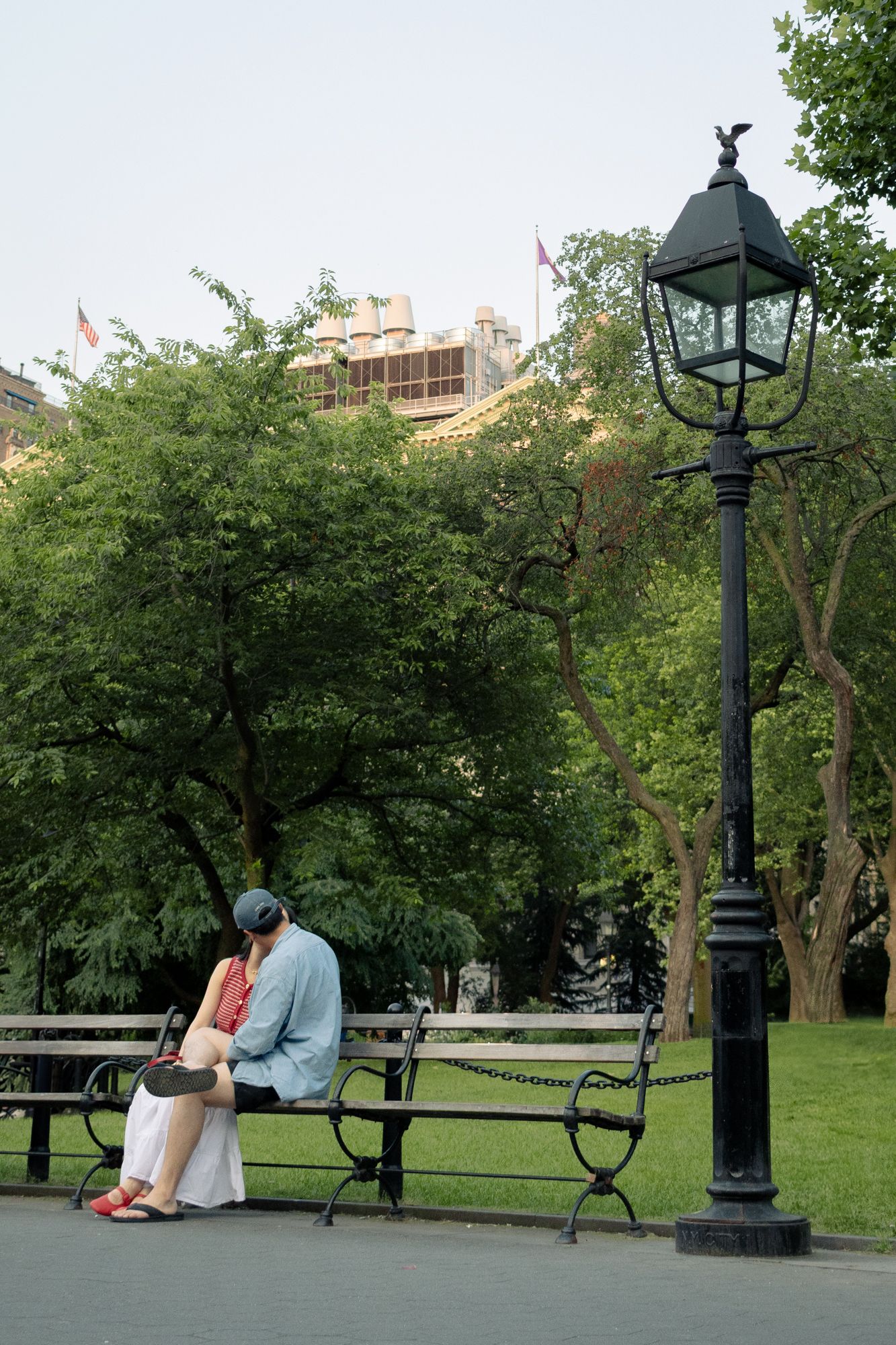 Vintage gas-style lampposts with eagle finials line a quiet park path, offering a glimpse into the historic charm of New York City’s parks.