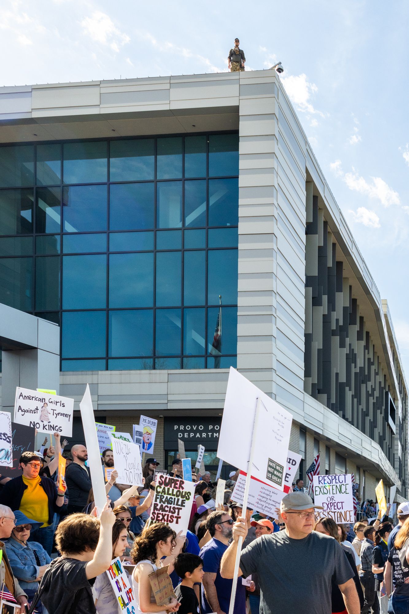A low-angle documentary shot capturing the scale of a demonstration outside the Provo Police Department.