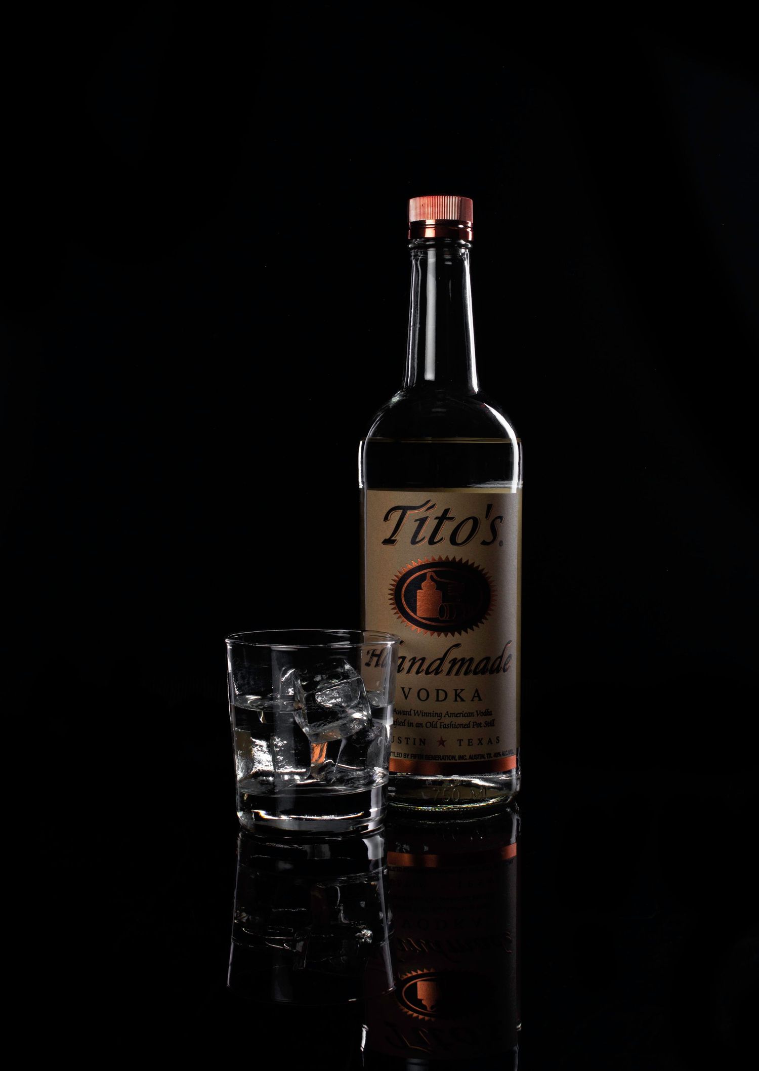 Sleek product photography of a Tito’s Vodka bottle and glass, using rim lighting and reflections to create a high-end, late-night aesthetic.