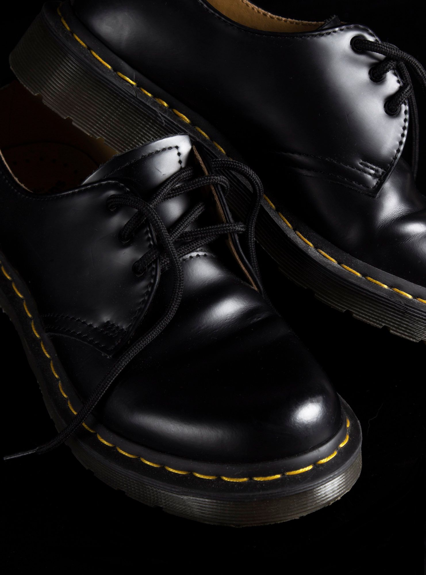 High-detail commercial product photography of leather footwear, featuring precision studio lighting to highlight texture and yellow stitches