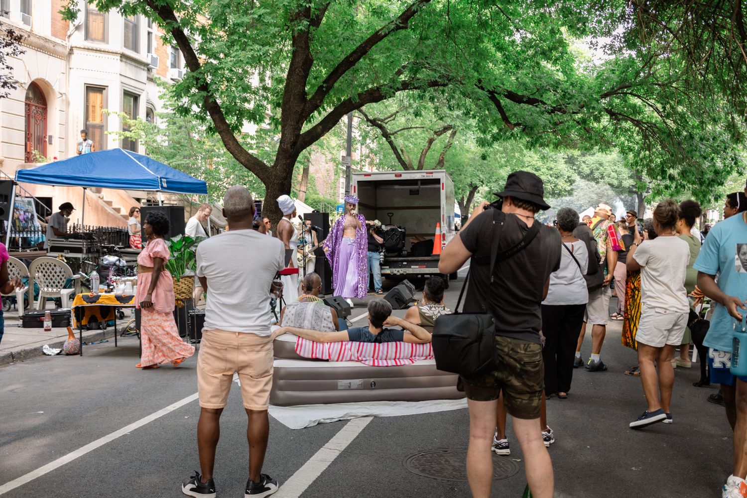 Capture the vibrant energy of a local street party, where community, music, and urban culture come alive under a canopy of summer trees. NYC