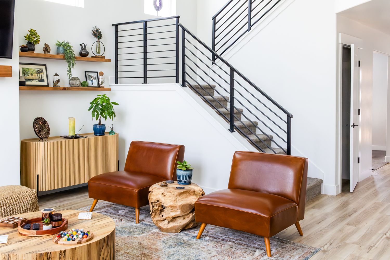 Bright, open-concept interior photography of a modern living area featuring a custom staircase, leather seating, and curated artisan decor.