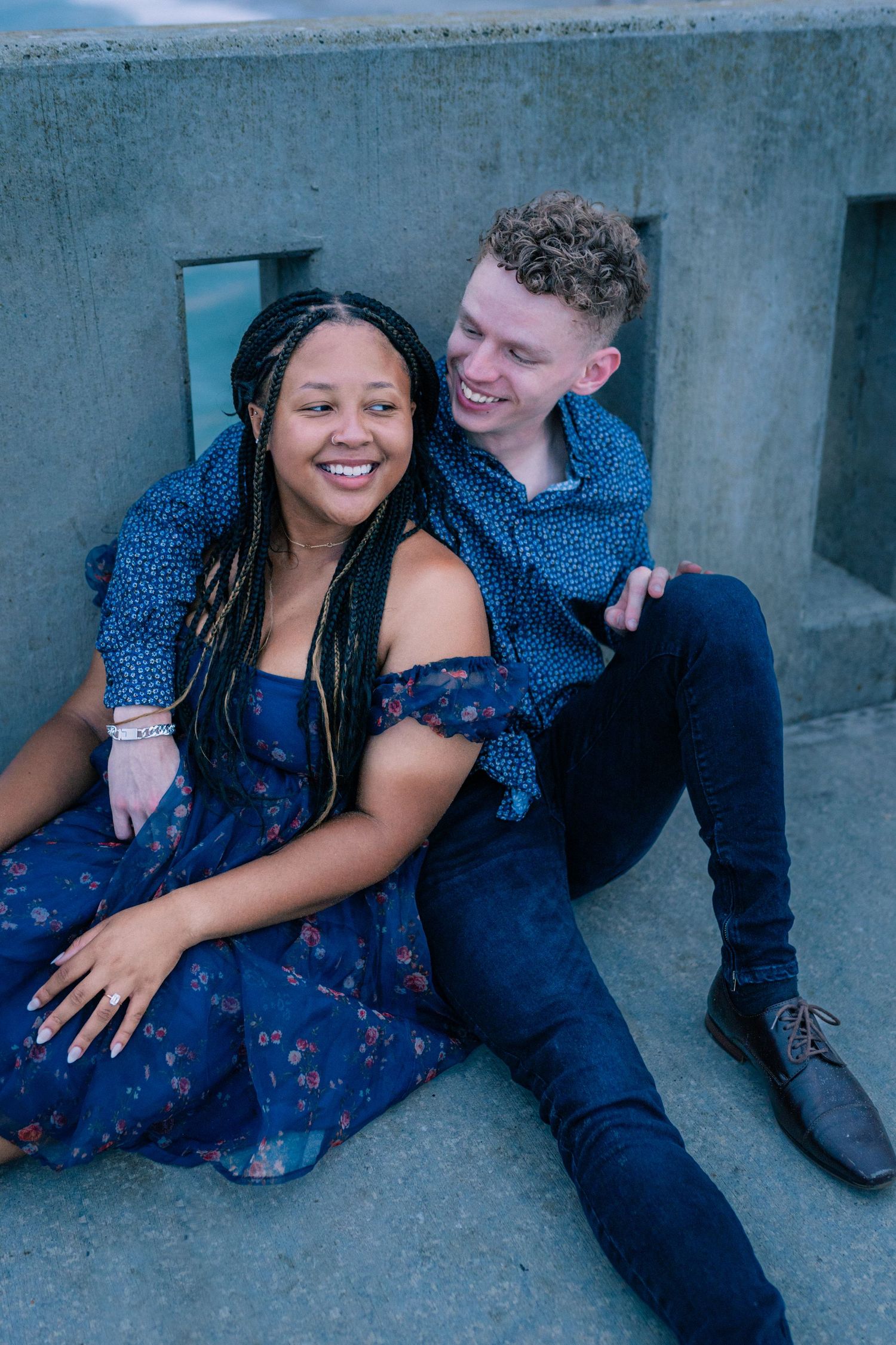 Couple sharing a candid moment while sitting on concrete steps outdoors.