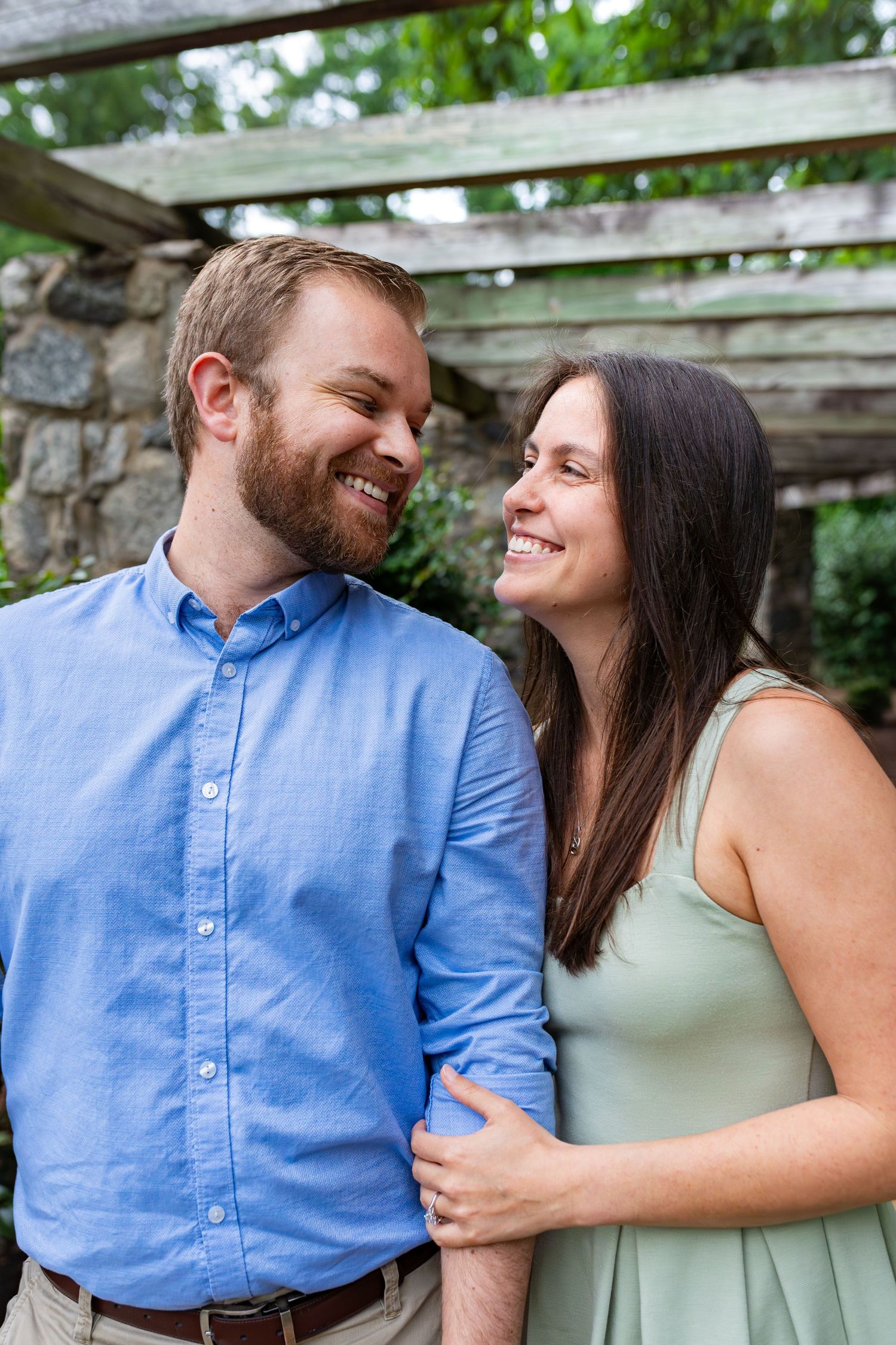 Couple sharing a joyful moment under a rustic wooden pergola.