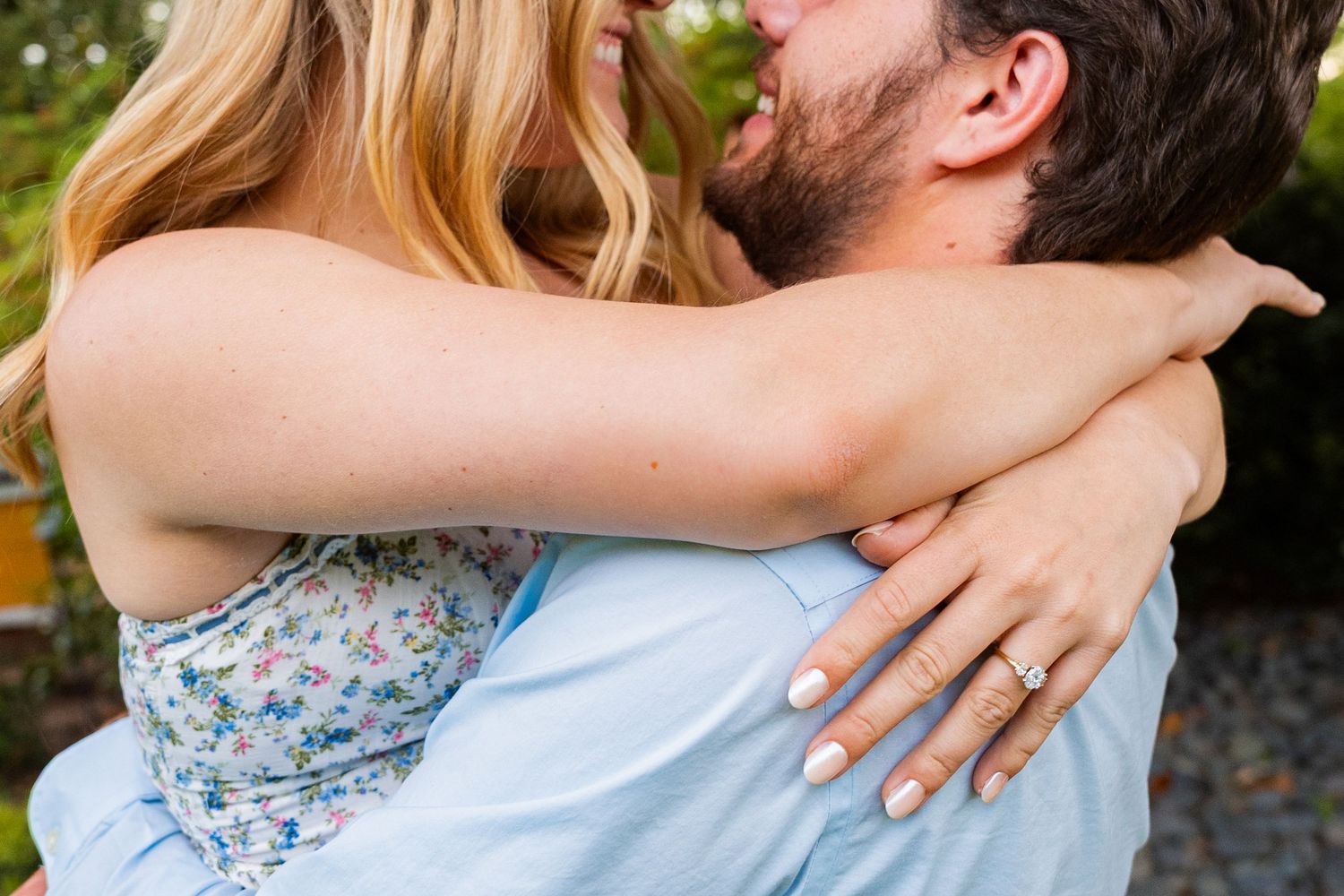 A tender embrace captured in detail showing hands and casual attire against a natural backdrop.